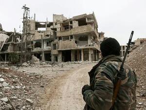 A Syrian opposition fighter from Failaq al-Rahman brigade carrying a sniper rifle walks down a street full of damaged and partially destroyed buildings on the frontline in the rebel-held enclave of Eastern Ghouta near Damascus on February 15, 2018 (AFP) 