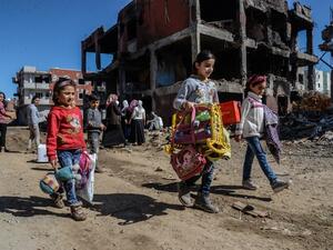 Young girls walk next to ruined houses and shops on March 8, 2016 during International Women's day in Cizre district. (AFP/Ilyas Akengin)