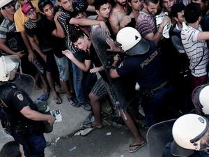 A policeman pushes a migrant as hundreds wait to complete a registration procedure by the police at a stadium on the Greek island of Kos on Aug. 12, 2015. (AFP/Angelos Tzortzinis)
