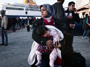 A woman holds her baby as migrants wait at the port of Piraeus on February 23, 2016 upon their arrival from the islands of Lesbos and Chios. (AFP/Louisa Gouliamaki)