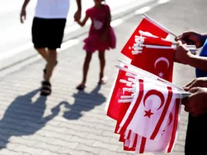 Greek officials and families at the memorial of soldiers killed in the 1974 coup (left). Tukish Cypriots holding their flags in a parade marking the 40th anniversary of Turkish invasion. (AFP/File)