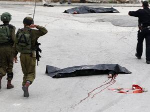 Israeli soldiers in Hebron near the bodies of two Palestinians who were killed after stabbing an IDF soldier. (AFP/File)