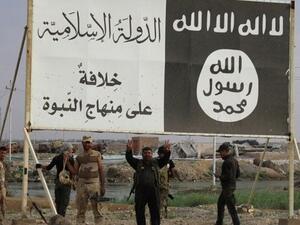 Iraqi fighters pose under Daesh posters near the town of Hit, Iraq. (Twitter)