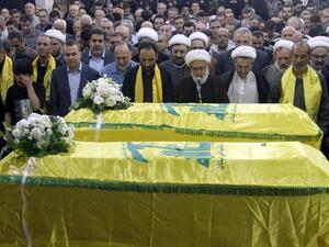 Members of Lebanon's Shiite movement Hezbollah pray in front the coffins of Shiite militants Khodr Aladdine and Hassan Bajouk during their funeral in the capital Beirut on May 8, 2015, after they were killed in combat alongside Syrian government forces in the Qalamoun region. (AFP/File) 