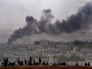 Kurdish people look at the Syrian town of Kobani from the Turkish side of the border. (AFP/Aris Messinis)