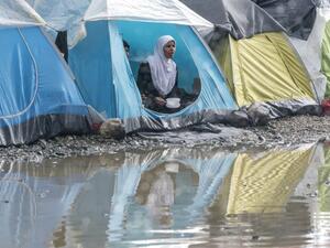 A refugee eats her dinner in a tent after a short rain at a makeshift camp for migrants and refugees at the Greek-Macedonian border near the village of Idomeni on April 24, 2016. (AFP/Joe Klamar)