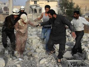 Syrian rescue workers and residents help an injured woman following a reported air strike by government forces on the rebel-held neighborhood of Haydariya in the northern city of Aleppo on April 10, 2016. (AFP/Thaer Mohammed)
