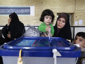 An Iranian woman holds a child to help her cast her ballot as she votes in the second round of parliamentary elections in Robat Karim, some 40 kms southwest of Tehran, on April 29, 2016. (AFP/Atta Kenare)