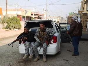 Armed tribesmen and Iraqi police sit in a car as clashes rage on in the Iraqi city of Ramadi, west of Baghdad, on January 2, 2014. [AFP]