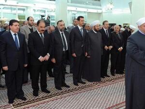 A handout picture released by the official Syrian Arab News Agency (SANA) shows Syrian President Bashar al-Assad next to Syrian Grand Mufti Ahmed Hassun and Syrian Prime Minister Wael al-Halaqi attending prayers on the eve of the anniversary of the birth of Islam's Prophet Mohammed at the al-Hamad mosque in Damascus. [AFP]