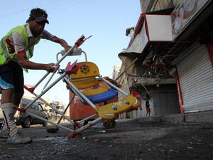 An Iraqi worker removes chairs as he cleans the site of a car bomb attack. (Image credit: AFP)