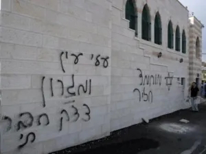 فلسطيني يتكلم على الهاتف في 5 ايلول/سبتمبر الى جانب كتابات بالعبرية على جدار مسجد في الضفة الغربية
