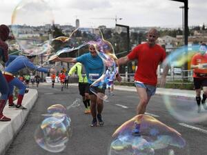 People dressed as "super heroes" make soap bubbles during the 6th Jerusalem's marathon, on March 18, 2016 in Jerusalem's Old City. (AFP/Thomas Coex)