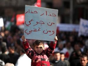 طفل يحمل شعارات تحذيرية خلال مسيرات ضد الغلاء في العاصمة الأردنية/أ.ف.ب