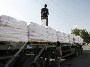 File photo of Palestinian workers offloading a truck full of aid in the Gaza Strip. (Abed Rahim Khatib/Flash90)