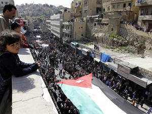 Thousands of Jordanians hold a giant national flag during a demonstration on March 4, 2011, in Amman to demand "regime reforms," a day after Prime Minister Maaruf Bakhit rejected calls for a constitutional monarchy. (AFP/Khalil Mazraawi)
