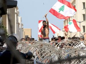 Lebanese protesters wave the national flag in front of a barbed wire fence as large crowds rally in Beirut on August 23, 2015. (Anwar Amro/ AFP) Lebanese protesters wave the national flag in front of a barbed wire fence as large crowds rally in Beirut on August 23, 2015. (Anwar Amro/ AFP)