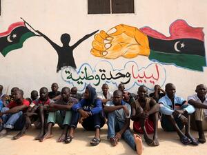 Illegal migrants sit in front of a painted wall on May 19, 2016 at the Abu Salim detention center in Tripoli, Libya. (AFP/Mahmud Turkia)