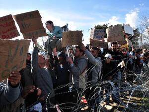 Men demonstrate near a barbed wire fence on 27 February, 2016 at the Idomeni camp on Greece's northern border with Macedonia, demanding that the Macedonian authorities let them in. (AFP/Sakis Mitrolidis)