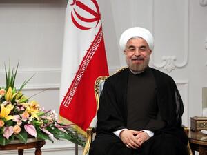 Iran's new President Hassan Rouhani sits next to the national flag on his first official day in office in Tehran on August 3, 2013. (AFP)