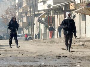 Rebel fighters, one holding a weapon, walk in a street on January 7, 2014 in the northern Syrian city of Aleppo. [AFP]
