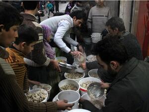 Syrian youths gather to receive aid food in the northern Syrian city of Aleppo on January 14, 2014. [AFP]