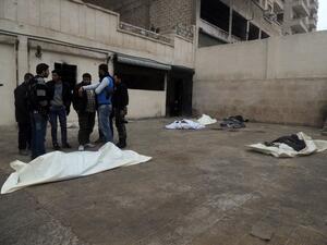 Rebel fighters talk near the bodies of the victims of a suicide bombing allegedly carried by al-Qaeda-linked group Islamic State of Iraq and the Levant's (ISIL) near the headquarters of the Army of the Mujahideen. [AFP]