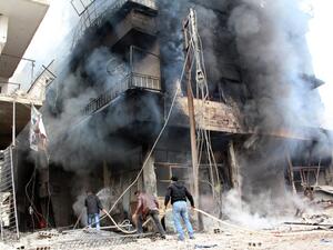 A picture taken on January 12, 2014, shows men trying to put out a fire in a buildings in the city of Daraya, southwest of the capital Damascus. [AFP]