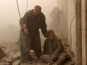 A Syrian man helps an injured man following an airstrike in Aleppo's Maadi neighborhood on December 17, 2013. [AFP]