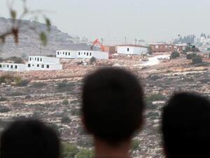 Palestinian children look at bungalows built by Israeli settlers on seized land, near the West Bank city of Birzeit on December 3, 2013. [AFP]