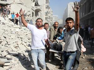 Syrians men evacuat a victim following an air strike by regime forces in the northern city of Aleppo on August 26, 2013. (AFP)