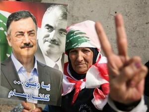 One of the mourners holds a picture of Hassan (left) with Rafiq Hariri (right): (picture courtesy of Hasan Shaaban/Daily Star)