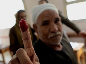 An Egyptian man shows his ink-stained finger after casting his vote on a new constitution at a polling station in Cairo on January 14, 2014. (AFP)