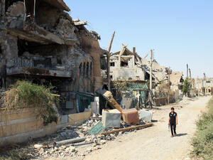 A Syrian rebel walks past buildings destroyed during fighting with pro-government forces along a street in a residential neighborhood of Syria's eastern town of Deir Ezzor (AFP/ABO SHUJA)