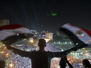 A Egyptian man waves national flags as an army helicopter flies over supporters of Egyptian Armed Forces General Ahmed Fattah al-Sisi rallying at Tahrir Square in Cairo (AFP/KHALED DESOUKI)