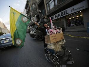 A Lebanese Shiite woman waves a Hezbollah and Amal movements flag as she pushes a cart past a Lebanese army forces checkpoint in the southern suburb of Beirut on September 23, 2013. Shells fired from Syria, where Hezbollah are fighting, hit northern Lebanese towns on Wednesday. (AFP)