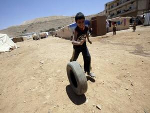 A Syrian child in a refugee camp in Lebanon plays with a tire.