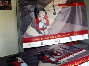 A poster that reads in Arabic, "break the wall of silence" (TOP) and "there is no excuse, every woman has the right to protection from violence" is held up at the offices of the Lebanese Council to Resist Violence Against Women (AFP/RAMZI HAIDAR)
