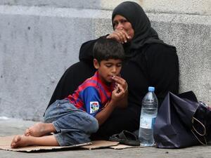 A Syrian mother and her child wait for food and help.