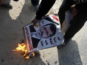 An opponent to the Muslim Brotherhood set fire to a portrait of ousted president Mohamed Morsi during a demonstration outside the Cairo police academy where his trial was set to take place before it was postponed until Feb. 1, 2014. (AFP)
