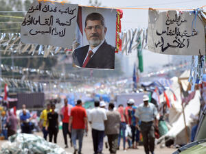 Supporters of Egypt's deposed president Mohamed Morsi walk past his portrait in Cairo (AFP/FAYEZ NURELDINE)