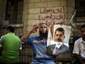 A supporter of Egypt's ousted president Mohammed Morsi holds a portrait of the former leader as he salutes during a demonstration outside the High Court in Cairo (AFP/GIANLUIGI GUERCIA)