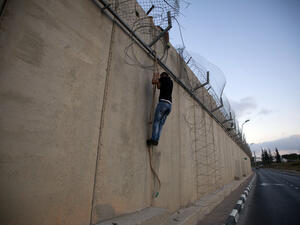 A Palestinian man jumps using a rope over a section of Israel's controversial concrete barrier that separates the West Bank from Jerusalem on August 12, 2013, in Beit Hanina, in Israeli annexed east Jerusalem. (AFP)