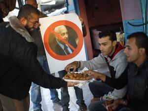 A Palestinian supporter of the Islamic Jihad distributes sweets in a street of the southern Gaza Strip town of Khan Yunis as a boy holds a poster bearing a portrait of former Israeli premier Ariel Sharon. (AFP)
