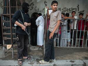 An armed man wearing a balaclava (ski mask) stands guard outside a bakery run by the Islamic rebel group "Ahrar Al-Sham", in the northern city of Raqqa (AFP/ALICE MARTINS)