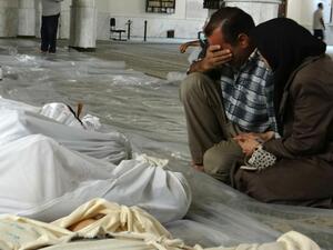 A Syrian couple mourns in front of bodies wrapped in shrouds ahead of funerals following what Syrian rebels claim to be a toxic gas attack by pro-government forces in eastern Ghouta, on the outskirts of Damascus on August 21, 2013. (AFP/Shaam News Network)