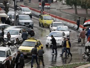 Syrians walk past cars in central Damascus on December 3, 2013 prior to a suicide attack in the Jebbeh district of the capital causing deaths and injuries, Syrian state television reported. (AFP)