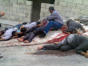 A Syrian man identifies the bodies from the massacre in the mountains outside the coastal city of Banias. (AP Image)