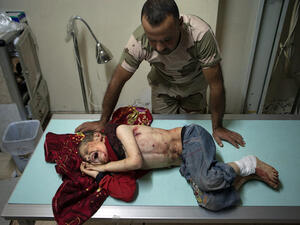 An opposition fighter stands over seven year old Ahmad Jabir, who was injured alongside some of his family members by a shell (Source: AFP/DANIEL LEAL OLIVAS)