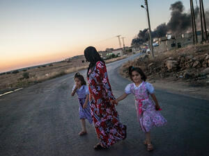 Syrian girls walk with their mother as she turns to look at smoke billowing from three shells dropped on the town of Al-Bara in the northwestern province of Idlib. (Source AFP/DANIEL LEAL-OLIVAS)